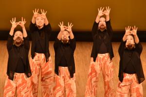 左右の親指と人差し指で輪を作り、輪を絡ませ頭上に手を挙げる手話ダンス表現