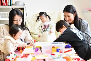 机の上に置かれたおもちゃで遊ぶ親子5人