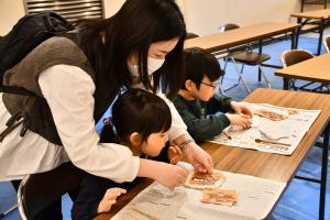 べんがら染めをする兄妹と手伝うお母さん