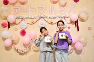 出来上がったシーグラスアートの作品を持って、フォトスポットでピースをする姉妹