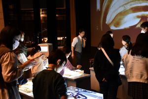 サンドアートを体験する人たちと説明するkoheiさん