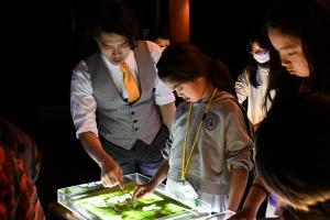 サンドアートを体験する女の子と指導するkoheiさん