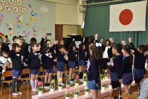 手を上にあげ、ポーズを取りながら歌う園児たち