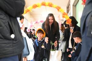 花飾りのアーケードを進むお母さんと園児