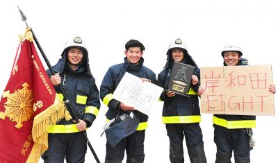 笑顔で表彰状や旗などを持つ消防士4人