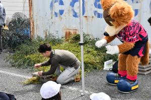 産卵床の作り方を説明する市職員と覗き込むロビーくん