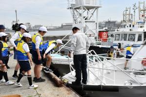 ライフジャケットを着て船に乗り込む児童たち