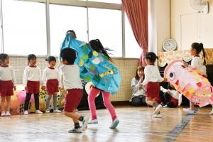 こいのぼりを持って走る園児