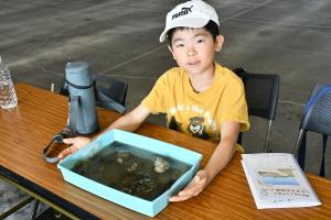 採集した生き物を入れたバットを持つ男の子