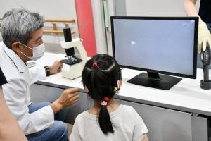 「お口のバイキンテスト」で先生と一緒にモニターを見る女の子