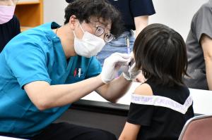 健診のブースで先生に歯を診てもらう女の子