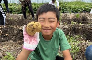 じゃがいもを持って笑顔の小学生の男の子