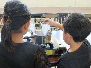 女の子と男の子がポリ袋でご飯を炊いている様子