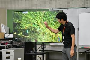 画面に映る産卵床と卵の説明をする柏尾学芸員