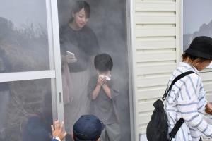 煙避難体験で、ハンカチで口を押さえて建物から出てくる男の子とお母さん