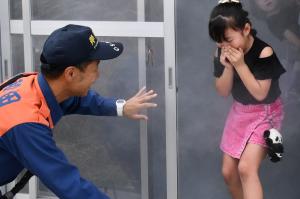 煙避難体験で、手で口を押さえながら建物から出てくる女の子