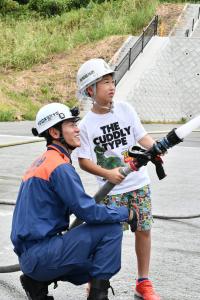 消防隊員と一緒に放水体験をする男の子