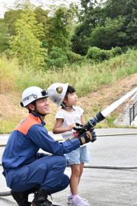 消防隊員と一緒に放水体験をする女の子