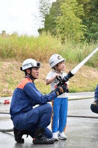 消防隊員と一緒に放水体験をする女の子