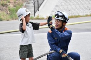 放水体験が終わり、消防士とタッチする男の子