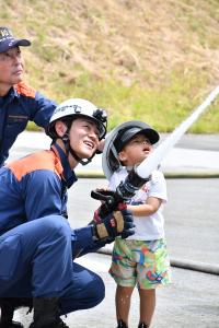 消防隊員と一緒に放水体験をする男の子
