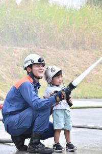 消防隊員と一緒に放水体験をする男の子