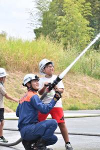 消防隊員と一緒に放水体験をする男の子