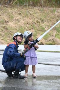 消防隊員と一緒に放水体験をする女の子