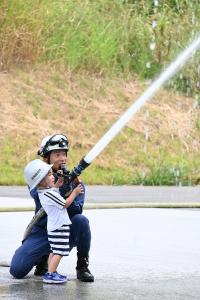 消防隊員と一緒に放水体験をする男の子