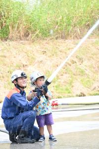 消防隊員と一緒に放水体験をする男の子