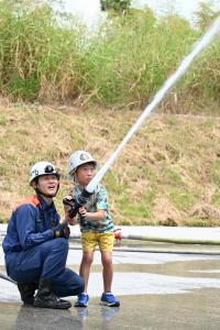 消防隊員と一緒に放水体験をする男の子