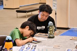 チョークアートをする男の子と見守る父