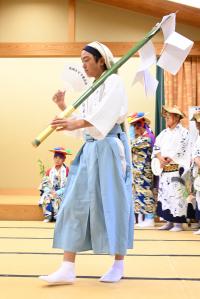 団扇で仰ぎながら歩く新発意