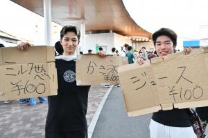 メニューをかいた段ボールを持っている二人の男の子