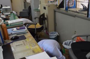 スーツを着た職員が机の下に隠れる様子