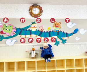 竜の壁面飾りの前に座る子ども